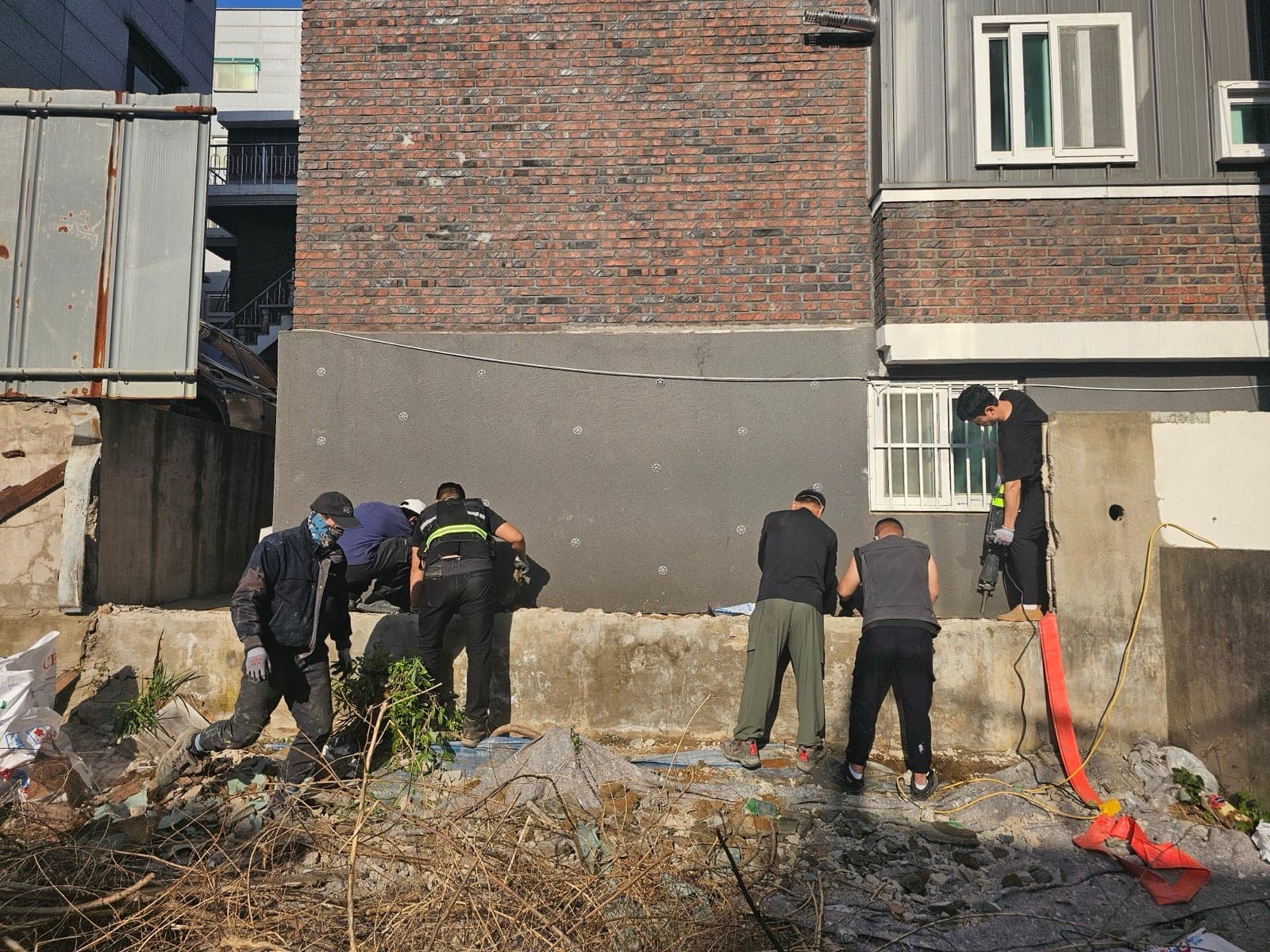 건물 외벽과 기초 주변 배관 보수 후 벽체 정리 작업 현장